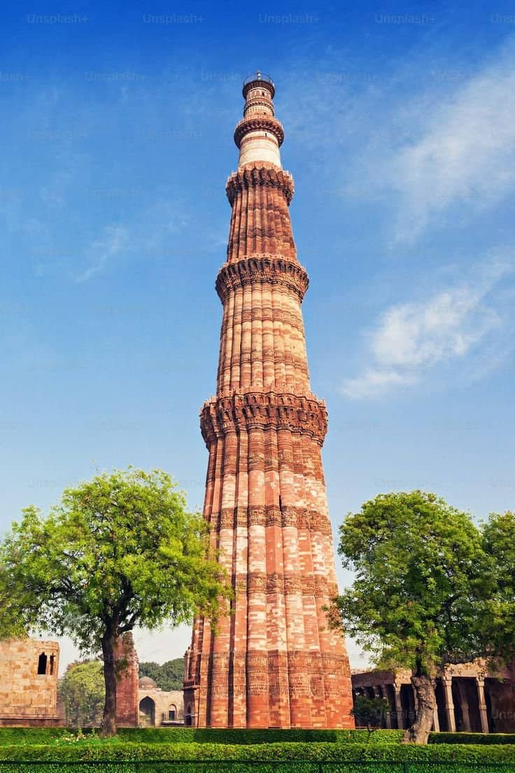 Towering UNESCO-listed Qutub Minar victory tower amidst lush heritage gardens in New Delhi